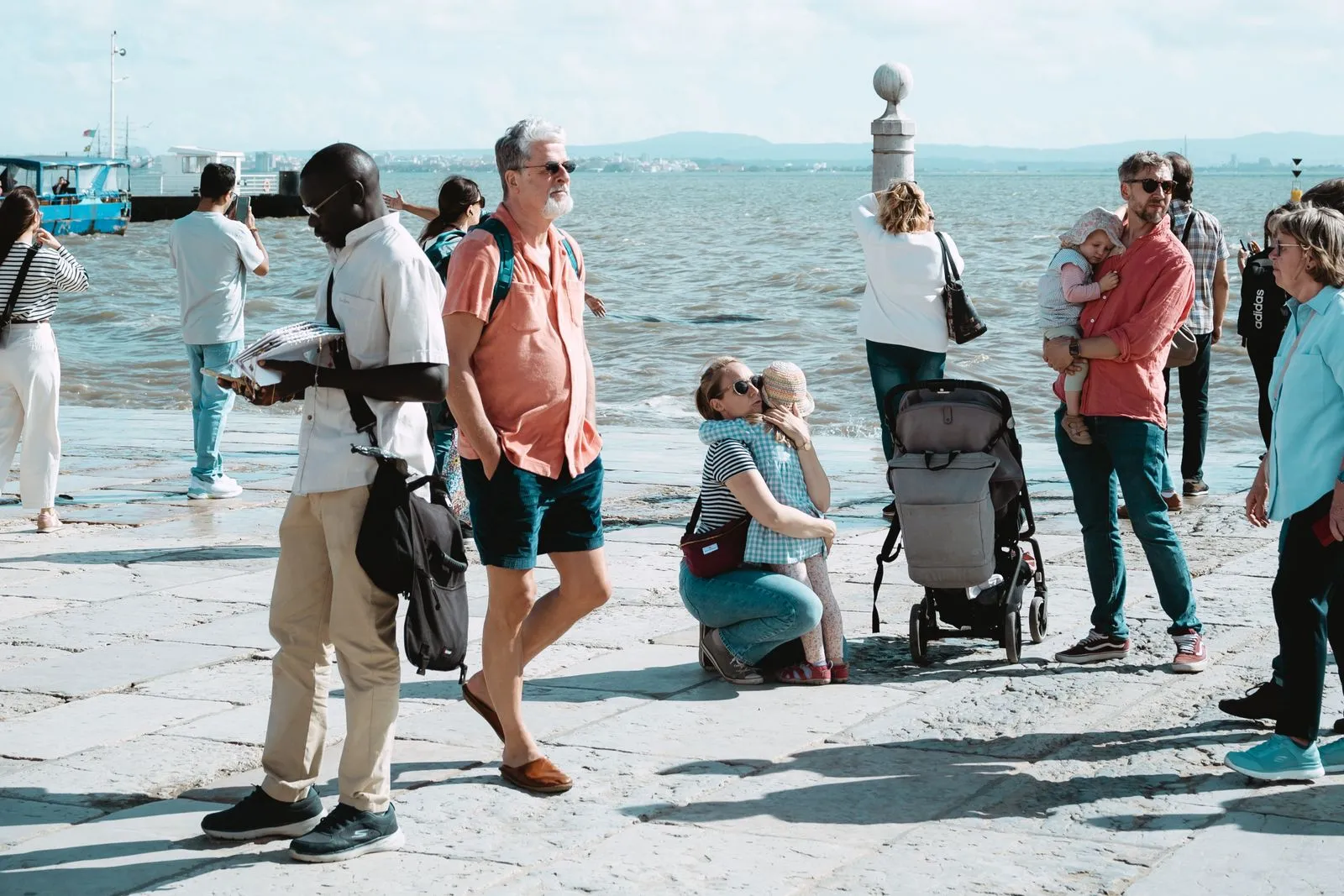 Group of adults and children enjoying a sunny day by the waterfront with a scenic view.